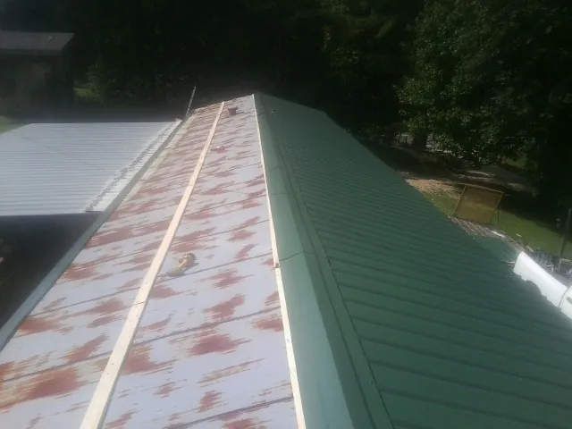Old rusted panels beside newly installed green metal roofing — Wind Damage Roof Repair by Roofing Brothers in Lenoir City