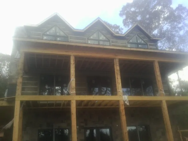 Dormers and porch framing on a large log home under construction — Roof Coating work by our crew in Lenoir City