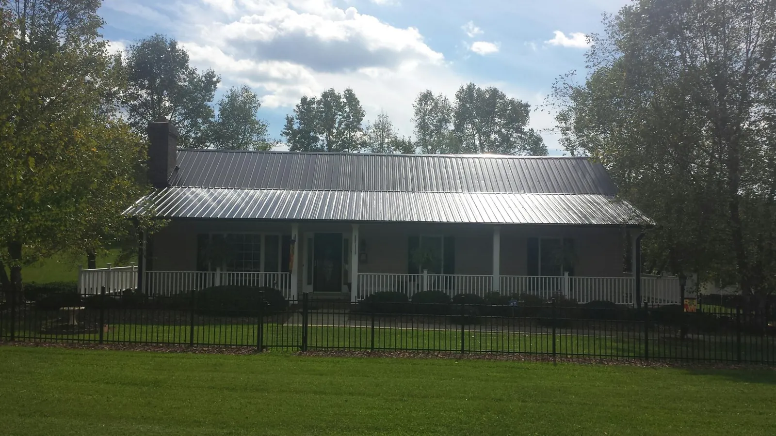 Gray metal roof on a brick ranch with a full width front porch — Gutter Guard Installation work by our crew in Lenoir City