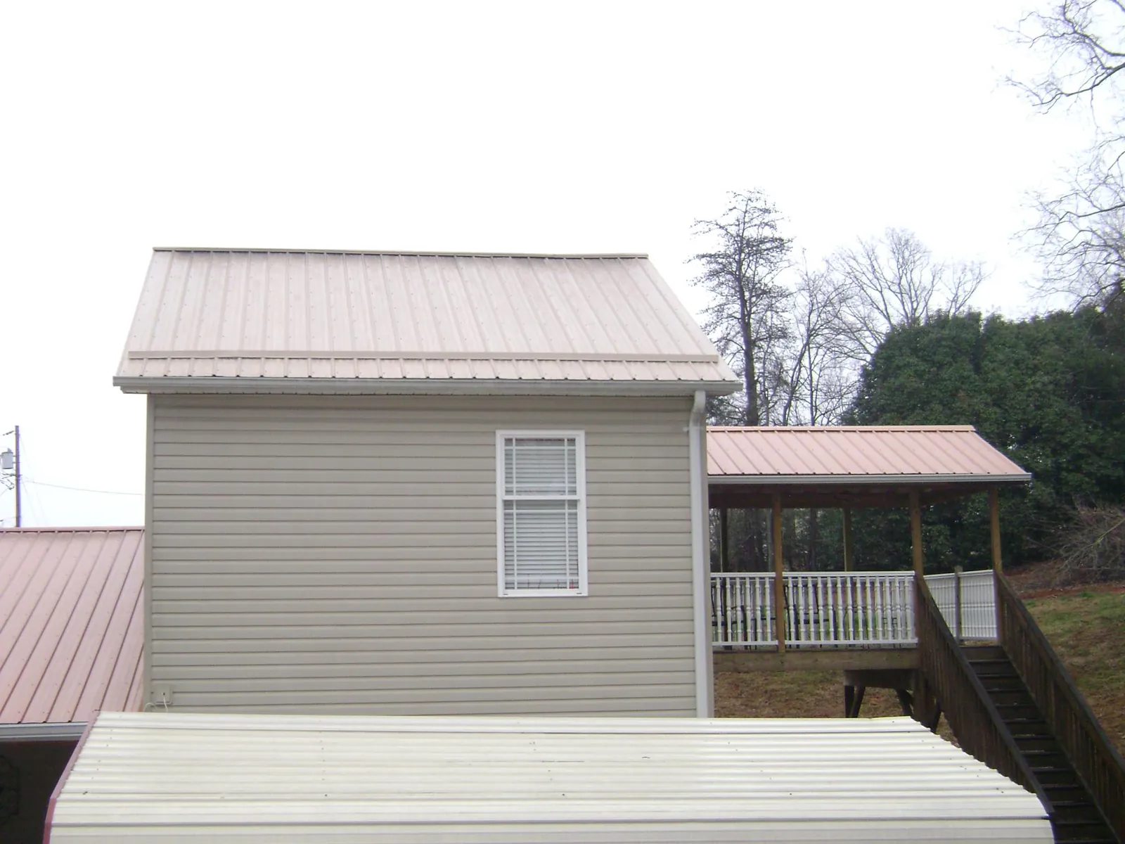 Tan metal roofs on a two story addition and attached porch, from a Roof Replacement job in Lenoir City