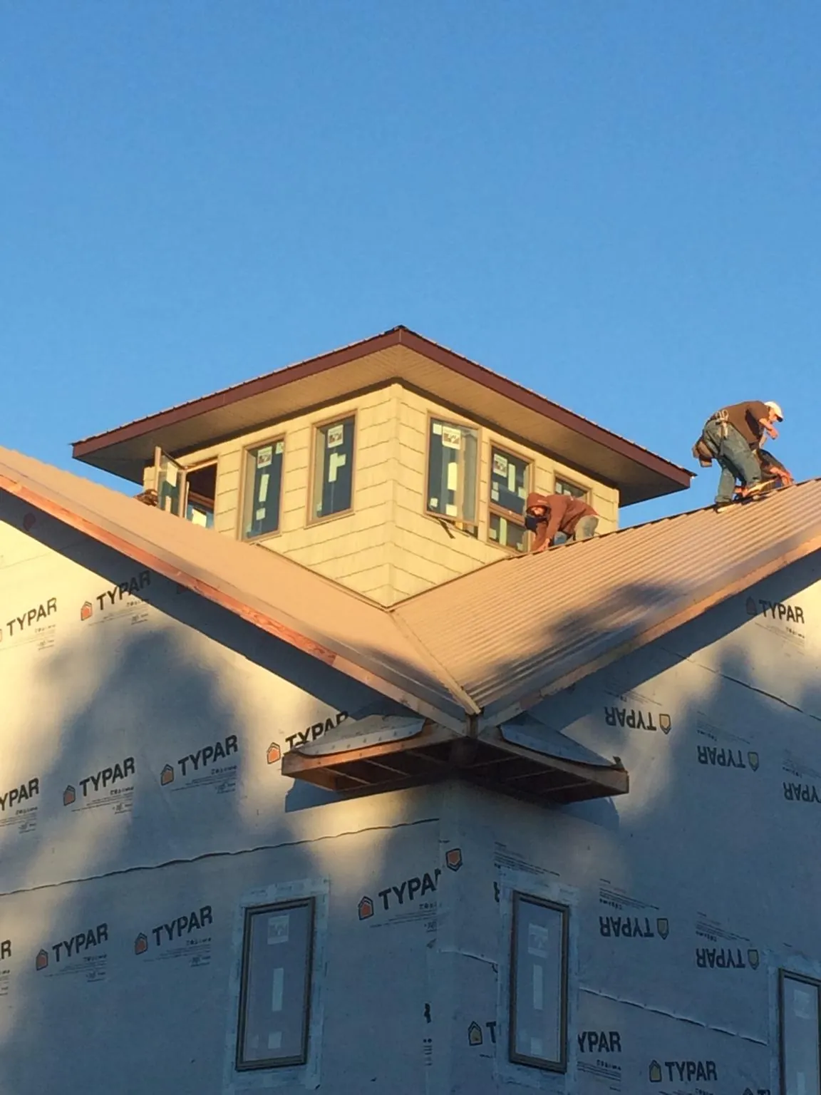 Roofers working around a rooftop cupola on a new metal roof at sunset — Roof Waterproofing in Lenoir City by Roofing Brothers
